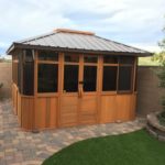 spa enclosure with brown metal roof on paved backyard