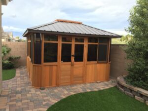 spa enclosure with brown metal roof on paved backyard